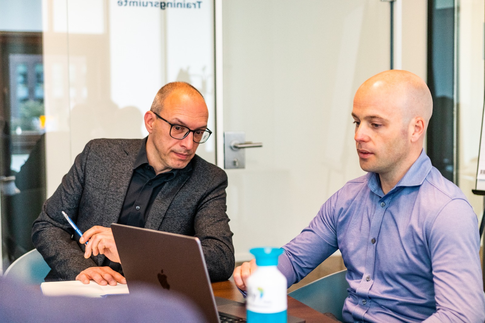 Two members of the Polly.Help team working together at a laptop